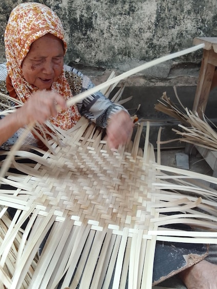 A person weaving with bamboo strips. 4