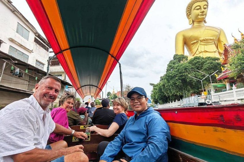 A group of people on a boat with a large golden statue in the background. 2