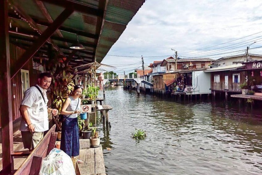 A riverside scene with a wooden dock, a bridge in the background, and houses along the water. 5