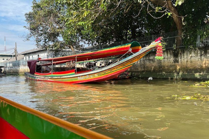 A colorful boat with a green canopy, docked near a tree-lined riverbank. 4