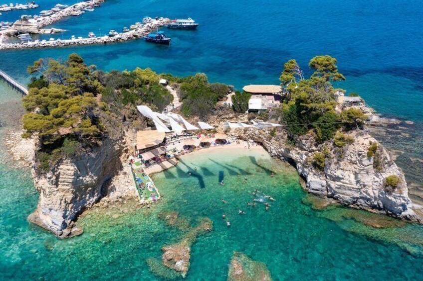 A coastal area with clear turquoise waters, rocky terrain, and a small beach with umbrellas. 4