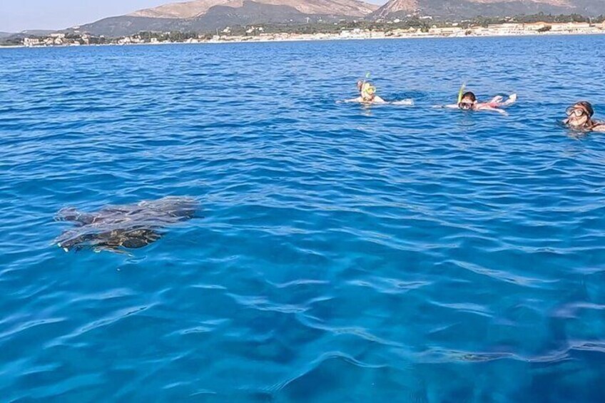A group of people snorkeling in clear blue water with a mountainous landscape in the background. 3