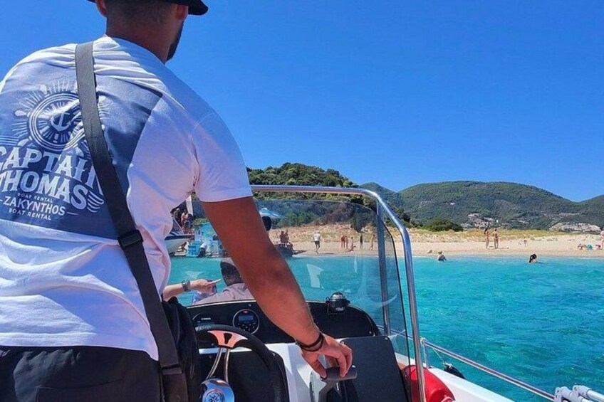 En person på en båt med fri sikt över en strand och vattnet. 3