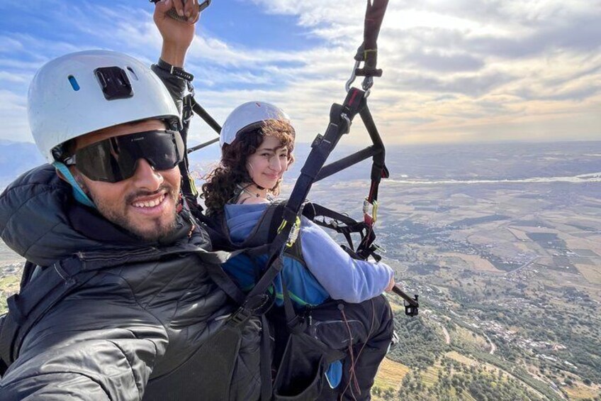 Two people in a tandem paragliding harness with a landscape view. 4