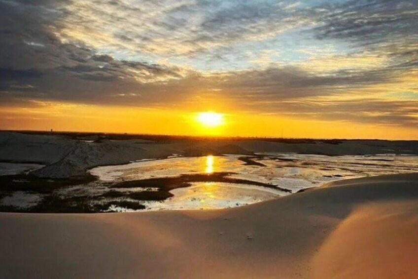 A sunset over a frozen landscape with reflective ice patches. 3