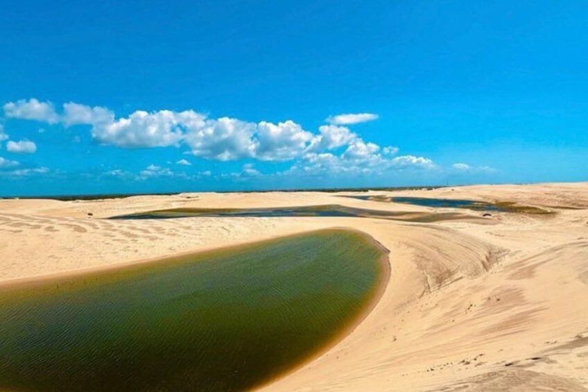 A desert landscape with sand dunes and a body of water. 2