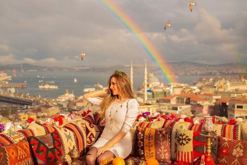 A person sitting on a colorful patterned couch with a cityscape and a rainbow in the background. 5