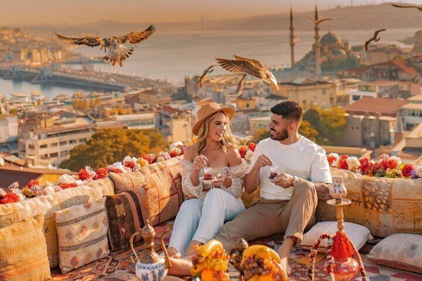 A couple sitting on a rooftop with a cityscape and birds in the background. 3