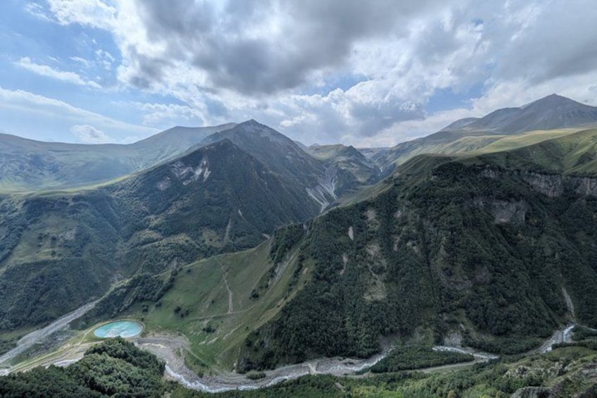 A mountainous landscape with a lake, winding roads, and dense forests. 4