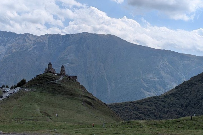 A mountainous landscape with a prominent hill featuring a small building with a dome and a bell tower. 3