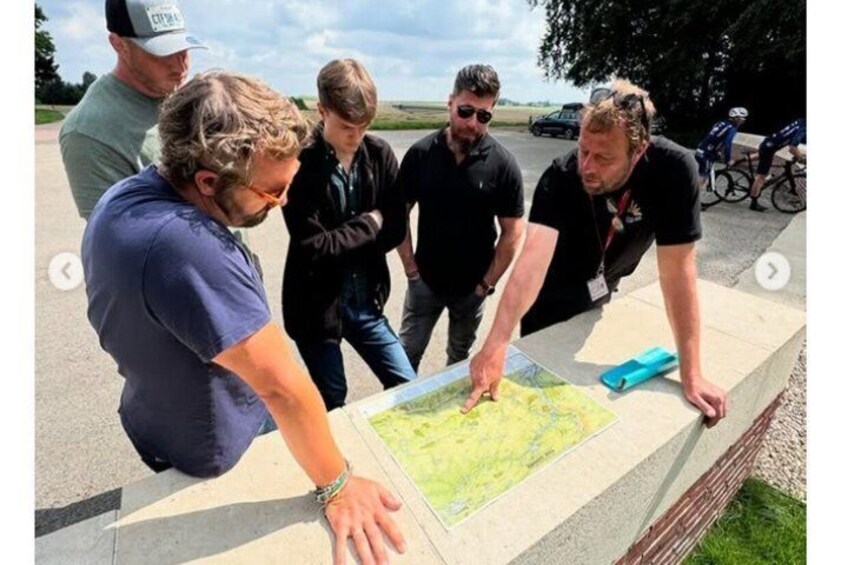 A group of people examining a map outdoors. 1