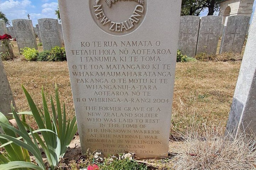 A gravestone with inscriptions in both Māori and English, surrounded by other gravestones in a cemetery. 5