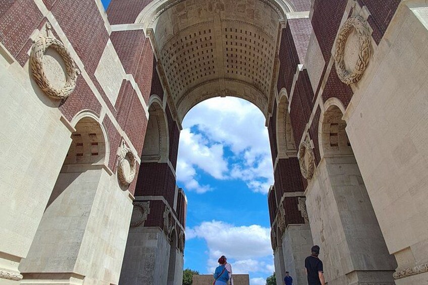An arched stone structure with intricate carvings and a clear blue sky above. 2