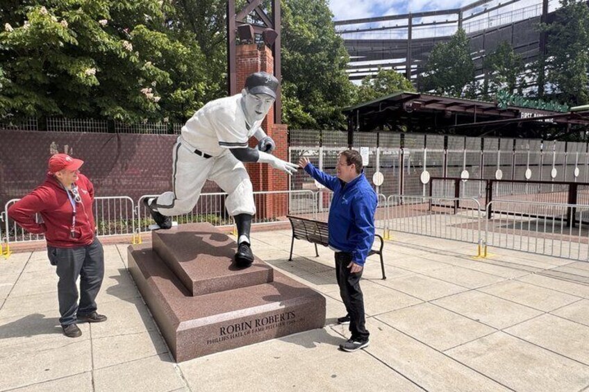 A baseball statue with a plaque reading 'ROBIN ROYER' in a public square with a fence and trees in the background. 5