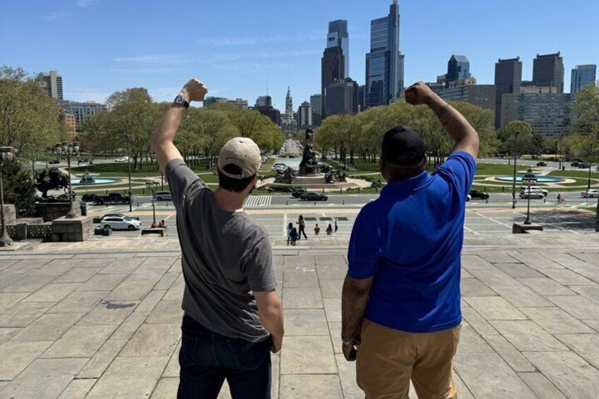 Two men standing in a park with a city skyline in the background. 3