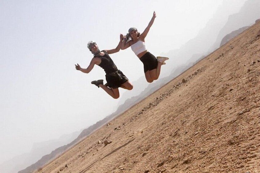 Two people jumping in mid-air in a desert landscape. 4
