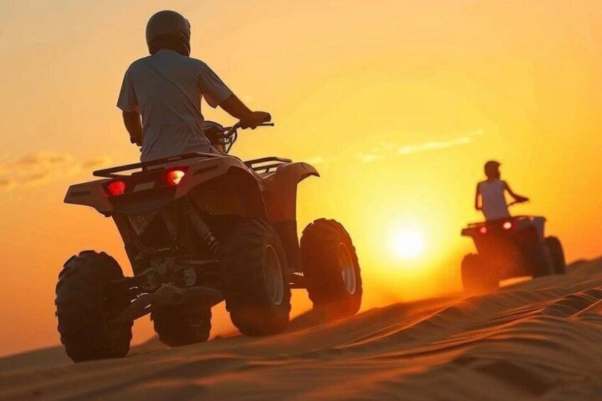 Two people riding ATVs on a sandy terrain during sunset. 1