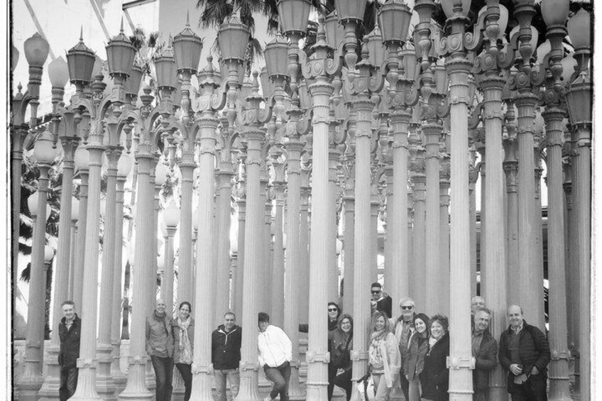 A group of people standing in front of a series of ornate columns with intricate designs. 1