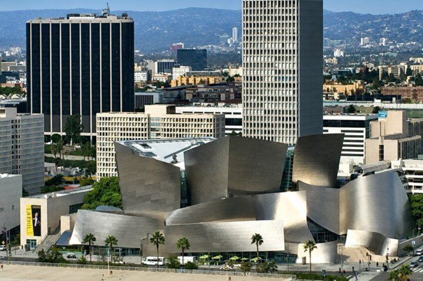 A modern architectural building with a unique, curved design, surrounded by a cityscape with various other buildings. 3