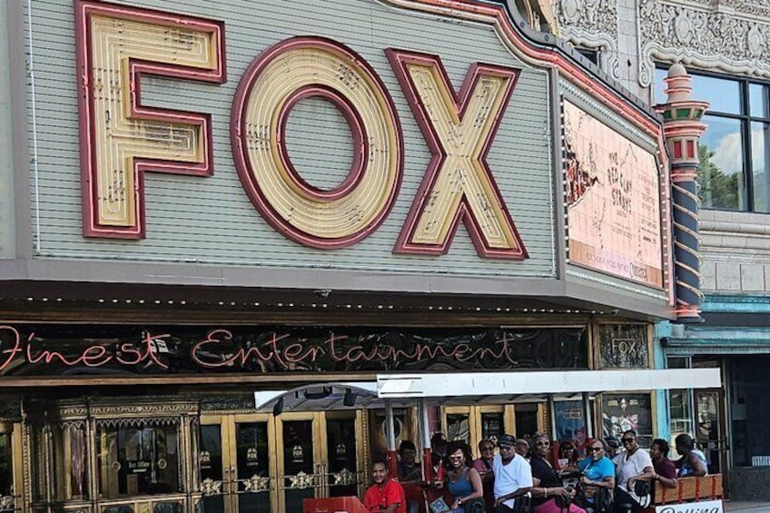 A theater with a large 'FOX' marquee and a crowd outside. 1
