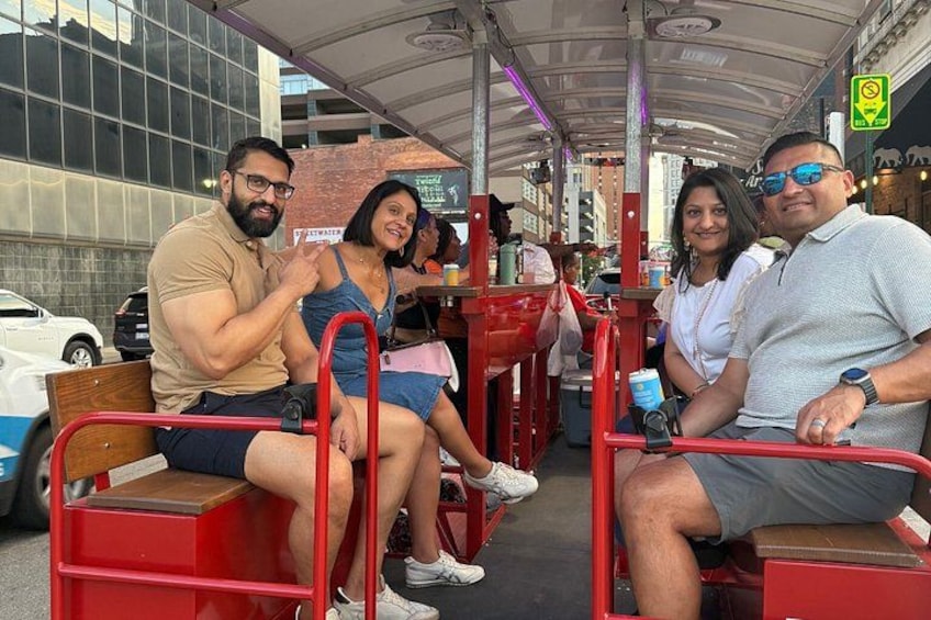 Un grupo de personas sentadas en sillas rojas en un café al aire libre, con un paisaje urbano de fondo. 5