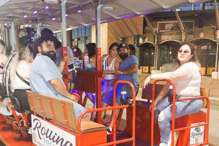 Un grupo de personas en una montaña rusa de madera con barandas naranjas y un letrero que dice 'Rolling'. 3
