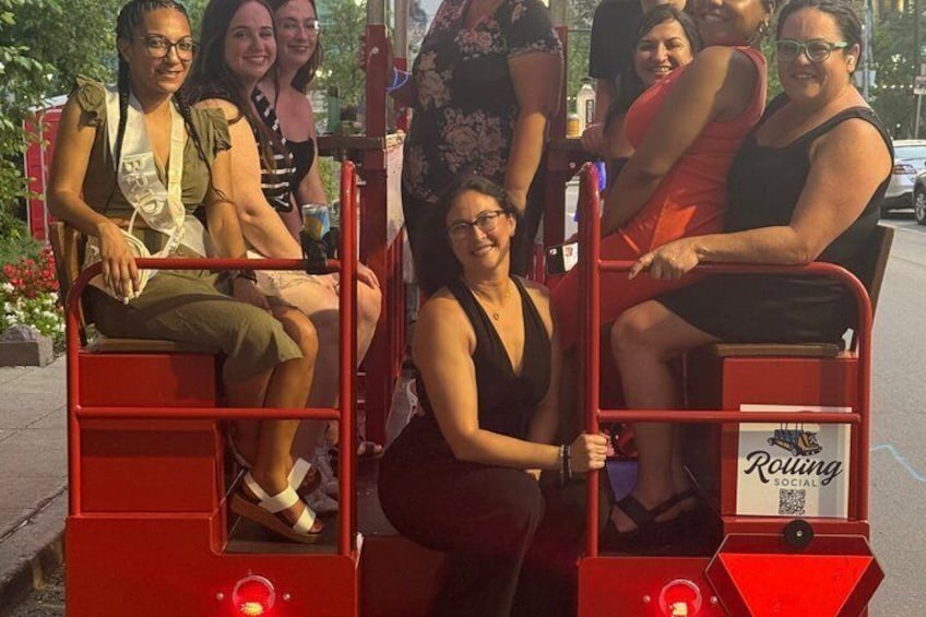 A group of people on a red trolley with a sign that reads 'Rolling Social.' 2