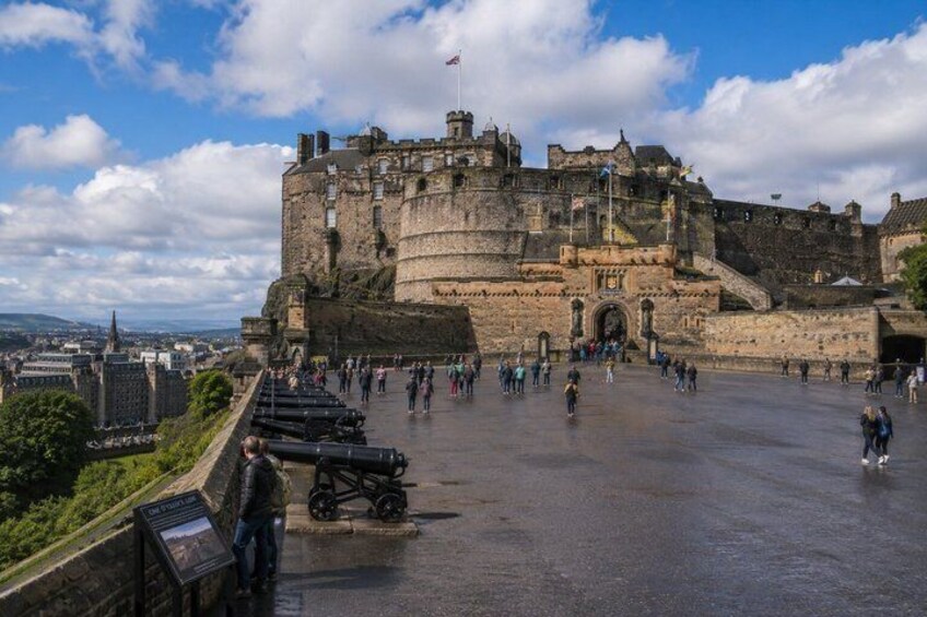 A historic castle with a moat, visitors, and a clear sky. 2