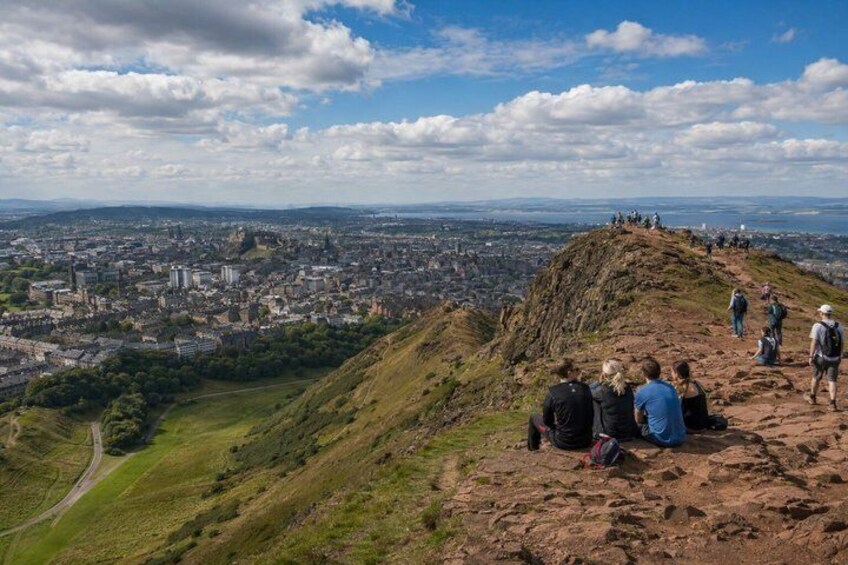 A group of hikers on a mountain ridge overlooking a city. 3