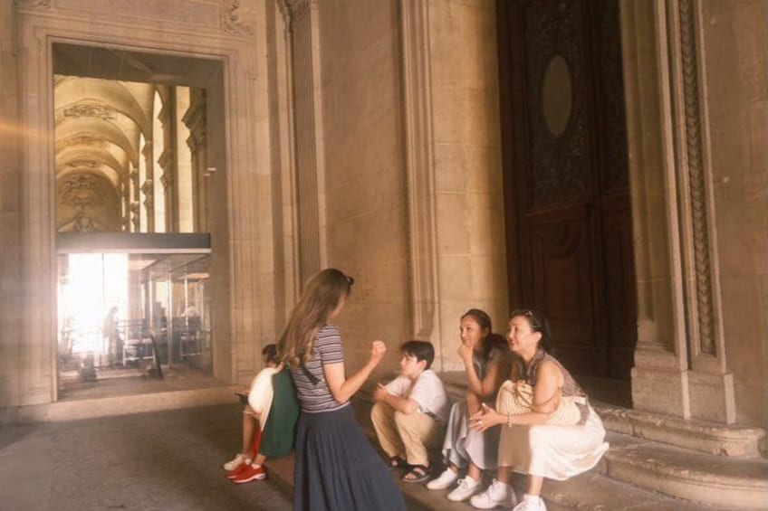 A group of people sitting on steps in a building with classical architecture. 5