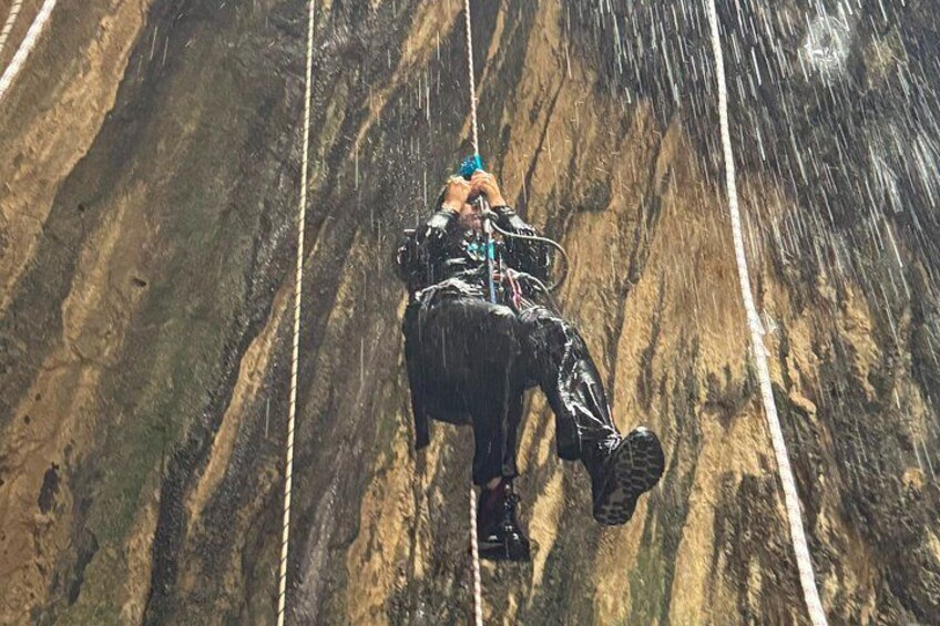 A person rappelling down a rocky cliff with ropes. 3