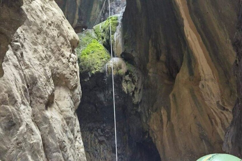 A canyon with a rope bridge and moss-covered rocks. 2