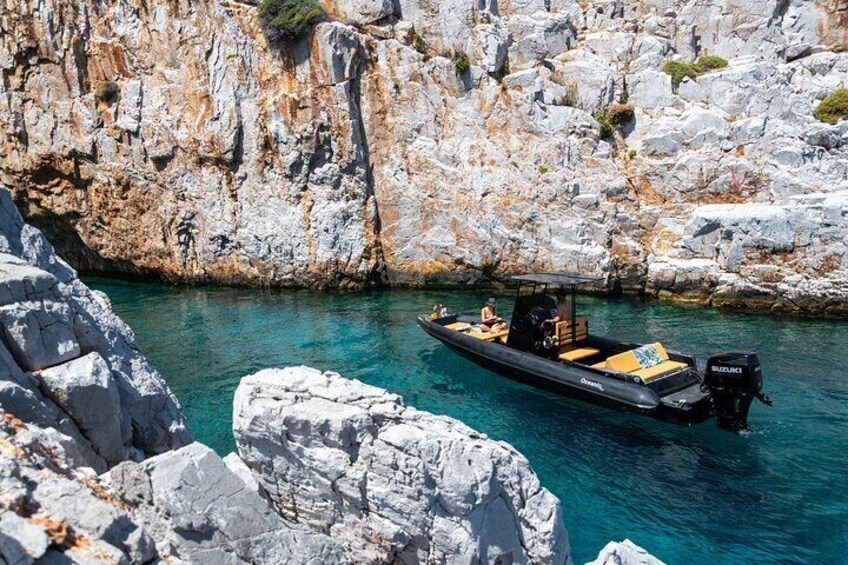 A small boat with a motor on a turquoise sea, surrounded by rocky cliffs. 5