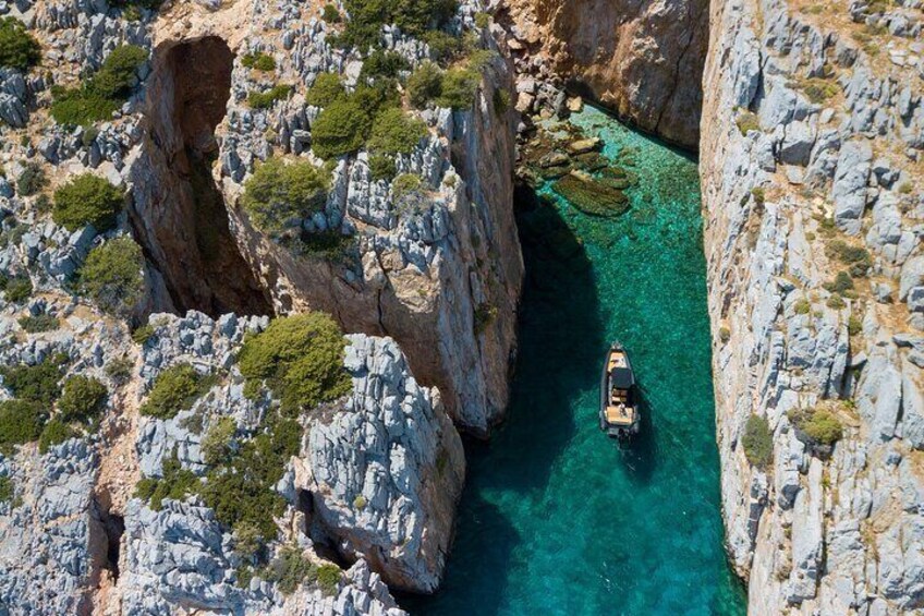 A boat in a narrow canyon with rocky cliffs and clear turquoise water. 3