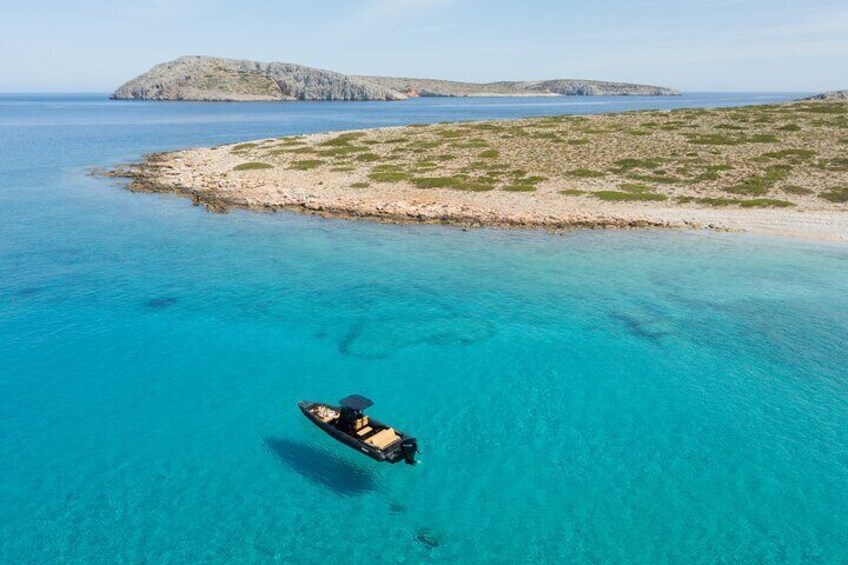 A boat on turquoise sea, rocky island in the background. 4