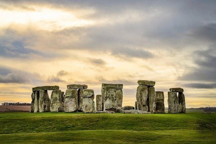 Stonehenge standing on a grassy field under a cloudy sky. 2