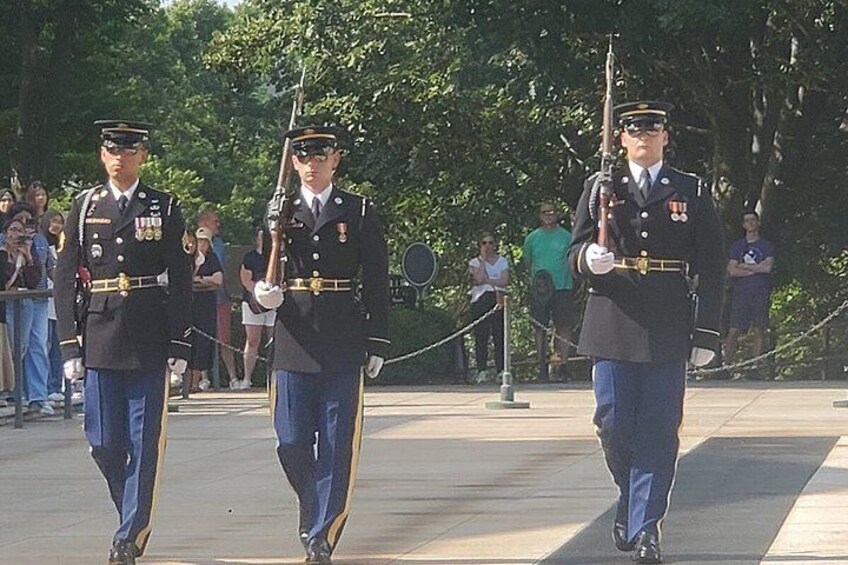Three military personnel in uniform marching in formation. 2