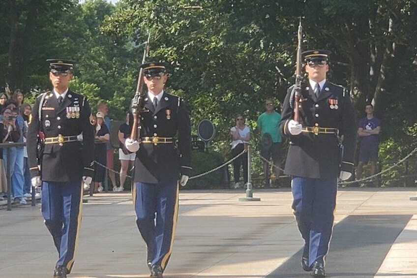 Three military personnel in uniform marching in formation. 1