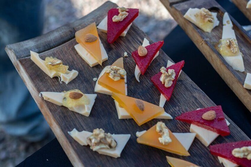 A wooden board with triangular cheese slices and nuts. 4