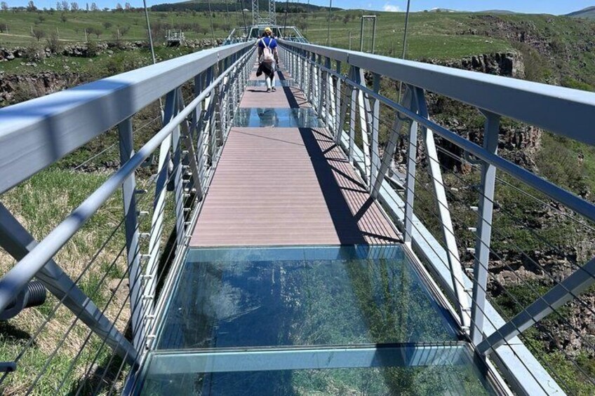 A pedestrian bridge with metal railings and a wooden walkway. 3