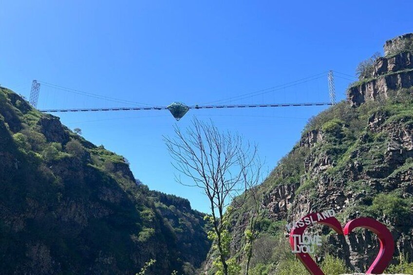 A suspension bridge, a heart-shaped sign, and a mountainous landscape. 4