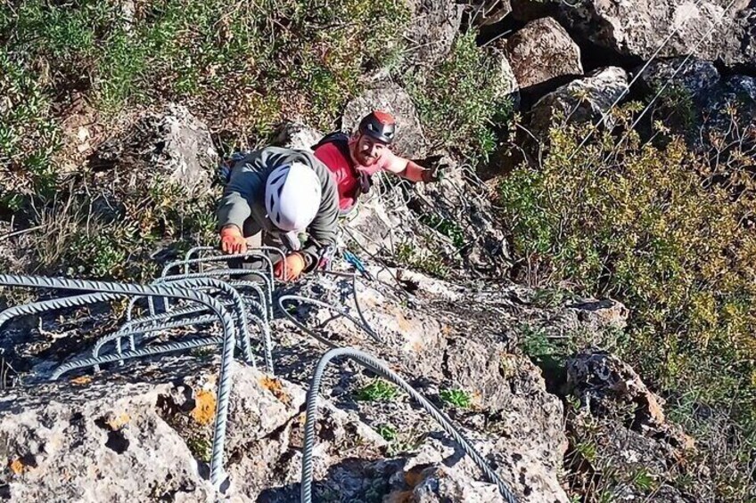 A person climbing a rocky terrain with metal cables. 3