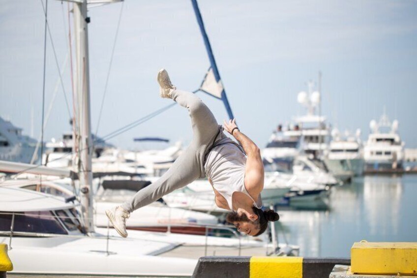 A person performing a handstand on a dock with boats in the background. 4