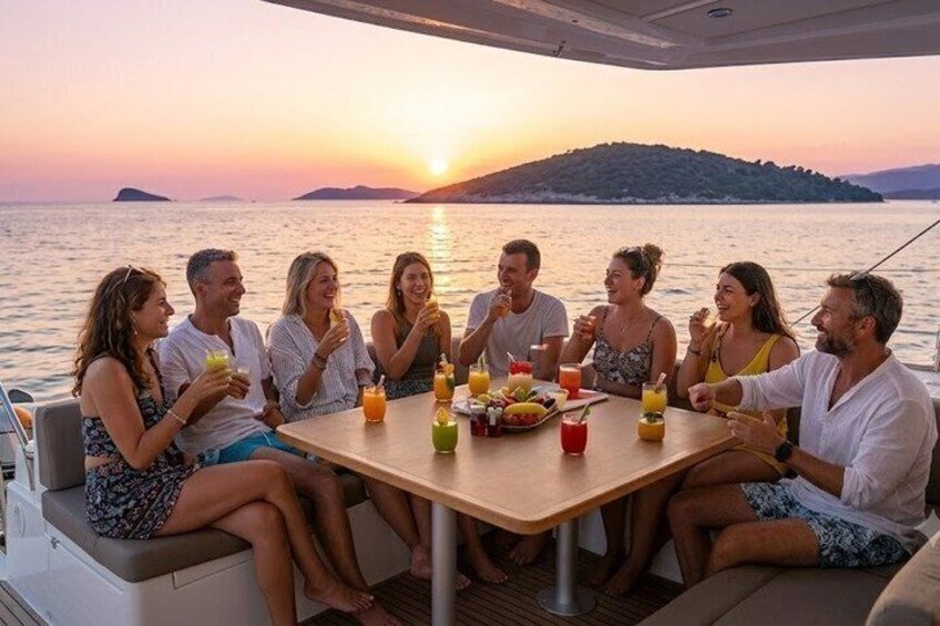 A group of people dining on a boat with a sunset in the background. 2