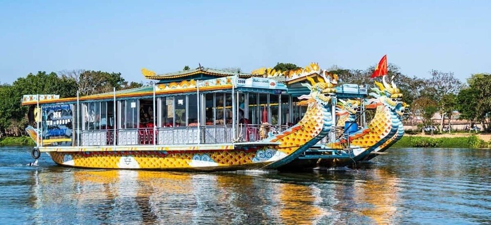 A dragon boat with a traditional design, featuring a dragon head and tail, and a red flag on top. 1