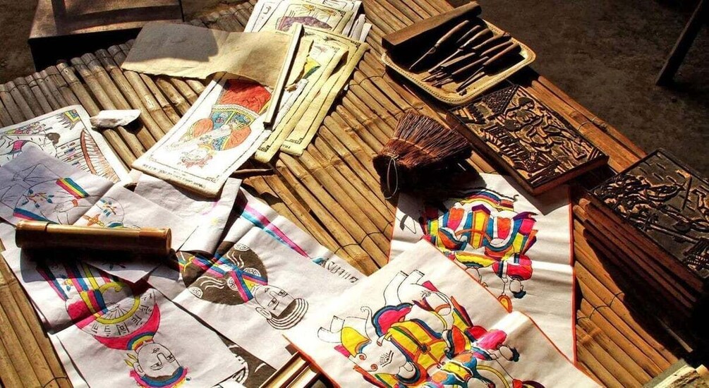 A table with various items including colorful cloths, wooden carvings, and currency notes. 2