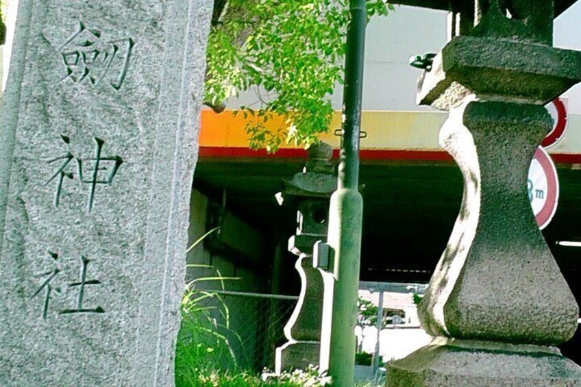 A stone monument with Chinese characters, a metal sculpture, and a red and white sign in the background. 4
