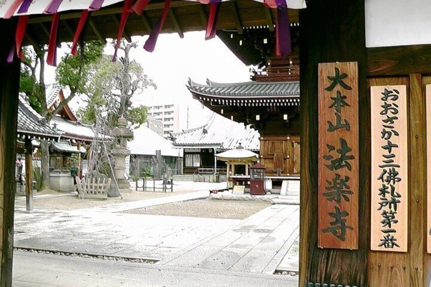 A traditional Japanese temple with a wooden structure, a stone lantern, and a signboard. 1