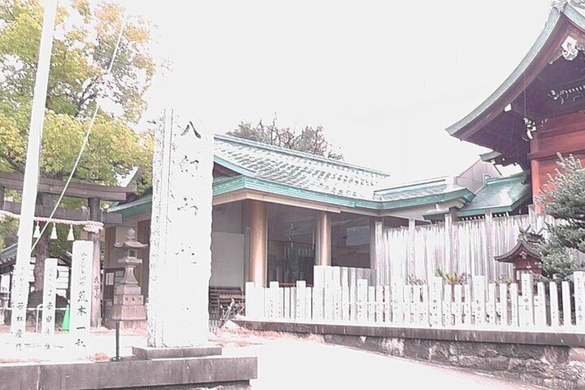 A traditional Japanese building with a tiled roof, wooden fence, and stone lanterns. 2