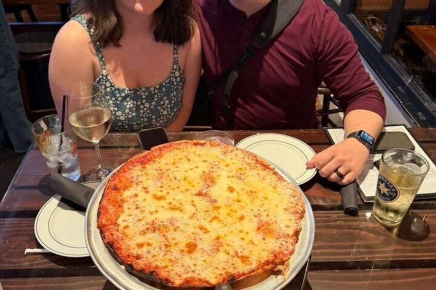 A large pizza on a table with a drink and a plate. 4